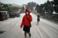 Indonesian students walk on a street covered with volcanic ash following an eruption of Mount Kelud, in Yogyakarta, Indonesia, Friday, Feb. 14, 2014. Volcanic ash from a major eruption in Indonesia shrouded a large swath of the country's most densely populated island on Friday, closed three international airports and sent thousands fleeing. (AP Photo/Slamet Riyadi)