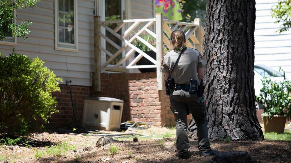 A officer carefully approaches the porch where a cobra was spotted. Law enforcement has blocked off Sandringham Drive as animal control officers continue to search for a missing cobra on June 30, 2021.