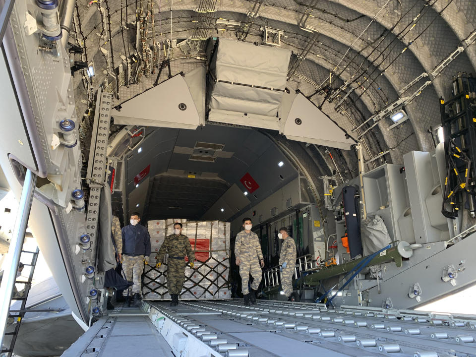 In this handout photo provided by the Turkish Defense Ministry, Turkish soldiers prepare to load a military cargo plane with Personal Protection Equipment donated by Turkey to help United States combat the new coronavirus outbreak, at the Etimesgut airport outside Ankara, Turkey, Tuesday, April 28, 2020. Turkey is sending a planeload of surgical masks, N95 masks and hazmat suits to U.S. to help the country battle the coronavirus outbreak.(Turkish Defence Ministry via AP)