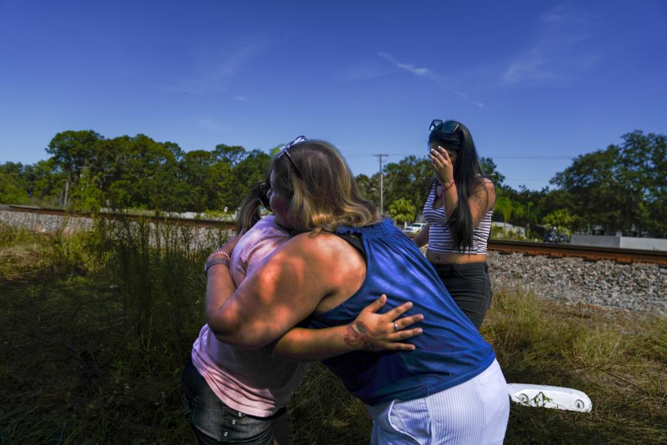 Leticia Hernandez, right, niece of Jose G. Hernandez who died alongside his wife and three children in a train collision on Saturday, receives a hug from women paying their respects at the site of the crash, Monday, Sept. 25, 2023 in Plant City, Fla. The weekend crash between a train and a sports-utility vehicle that killed six people in Florida happened at a private road crossing where little more than a sign or two is required, no crossing gates, no flashing lights, no sound. (Martha Asencio-Rhine/Tampa Bay Times via AP)