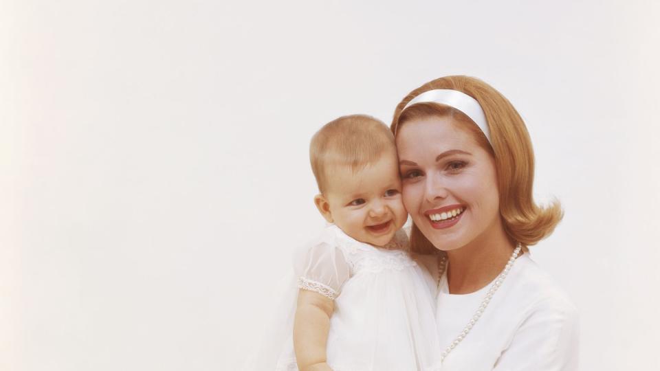 mother holding baby daughter against white background