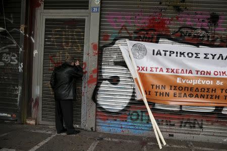 A protester looks through the closed entrance of the Labour ministry during a protest of Greek doctors against planned pension reforms in Athens, Greece, January 25, 2016. REUTERS/Alkis Konstantinidis