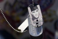 A relative of SP4 Donald Sargent wears his dog tags at the unveiling of a monument to honor the military passengers of Flying Tiger Line Flight 739, Saturday, May 15, 2021, in Columbia Falls, Maine. Sargent, was among those killed on the secret mission to Vietnam in 1962. (AP Photo/Robert F. Bukaty)