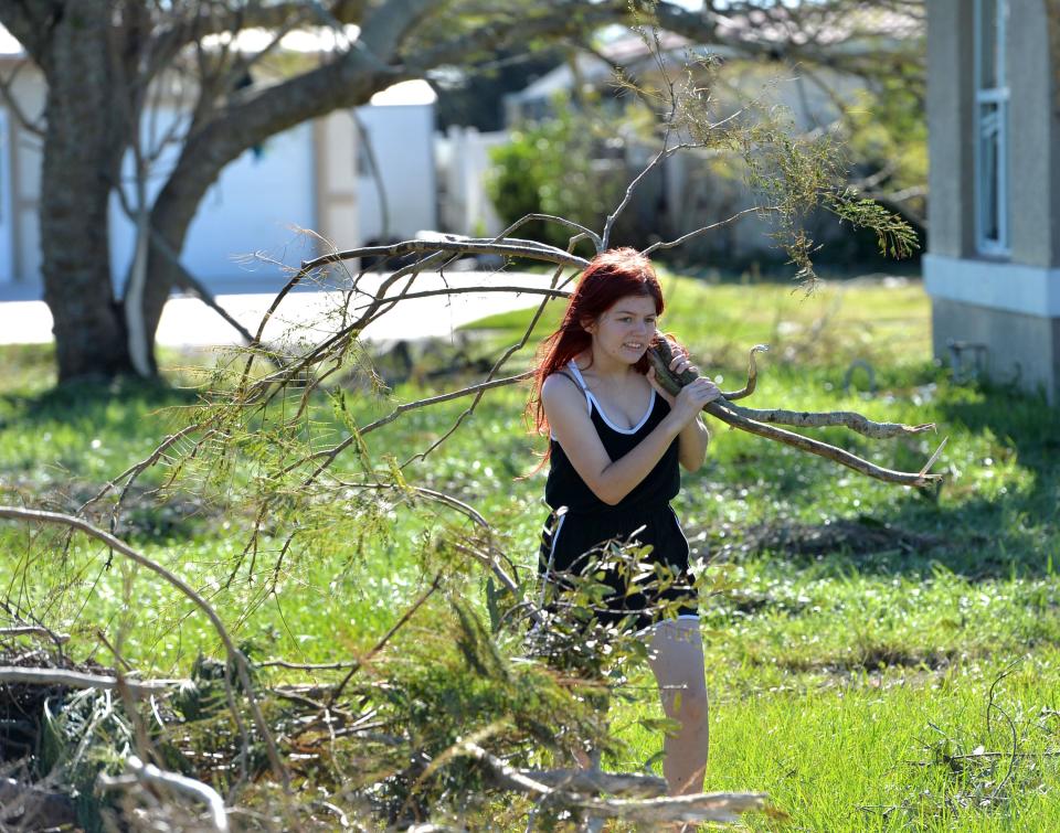 Selena Benitez, 16, carries branches for a Jacaranda tree in her family's yard, to a pile of yard debris in front of the home on Floral Ln. in Port Charlotte, Florida, following Hurricane Ian on Friday, Sept. 30, 2022. Benitez said she has helped three other neighbors clean up their yards. "There's lots to pick up", she added. 