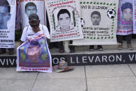 A relative of one of the 43 missing university students holds a placard with s photo of his loved one, as he joins others in a march on the seventh anniversary of their disappearance, in Mexico City, Sunday, Sept. 26, 2021. Relatives continue to demand justice for the Ayotzinapa students who were allegedly taken from the buses by the local police and handed over to a gang of drug traffickers. (AP Photo/Marco Ugarte)