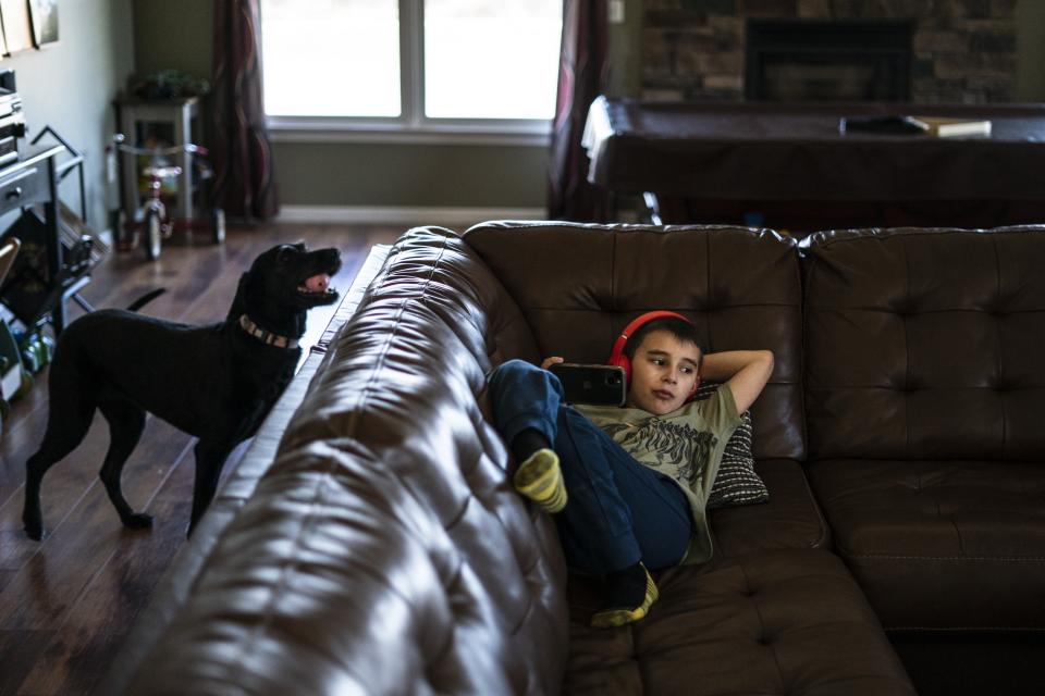 Jessica Conard's son Noah, 10, relaxes at their home in East Palestine, Ohio, Tuesday, March 7, 2023. Jessica wonders after the train derailment if her kids will ever be able to fish in the pond separating their property from the railroad tracks. Or play at the park where the chemicals are being removed from a stream. Can they remain in the town where "generations upon generations" of family have lived? (AP Photo/Matt Rourke)