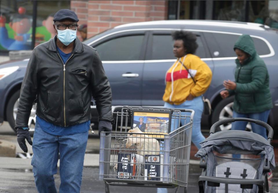 A man covers his face with a mask while shopping at Pick 'N Save near 60th and Capitol, Saturday, March 29,2020.  The neighborhood  is located in a hot spot for coronavirus in Milwaukee according to a map by Milwaukee County Office of Emergency Management.