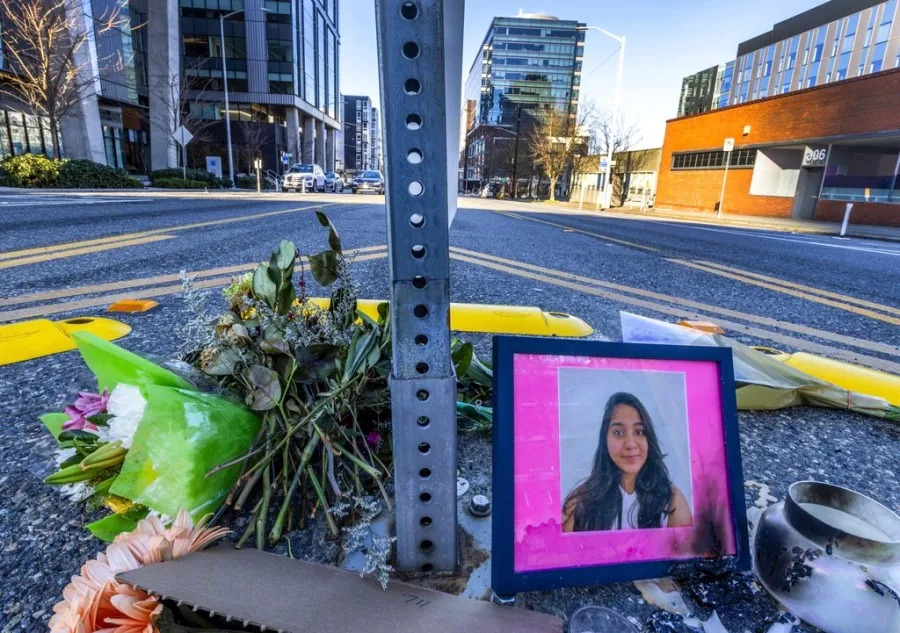 A photo of Jaahnavi Kandula is displayed with flowers, Sunday, Jan. 29, 2023 in Seattle, at the intersection where she was killed by a Seattle Police officer driving north while responding to a nearby medical incident. A city watchdog agency is investigating after a body-worn camera captured one Seattle Police Department union leader joking with another following the death of a Kandula, who was struck and killed by a police cruiser as she was crossing a street. (Ken Lambert/The Seattle Times via AP)