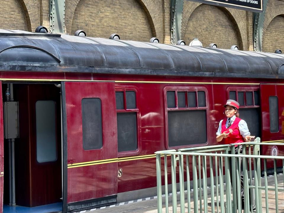 conductor standing in front of the hogwarts express at universal orlando