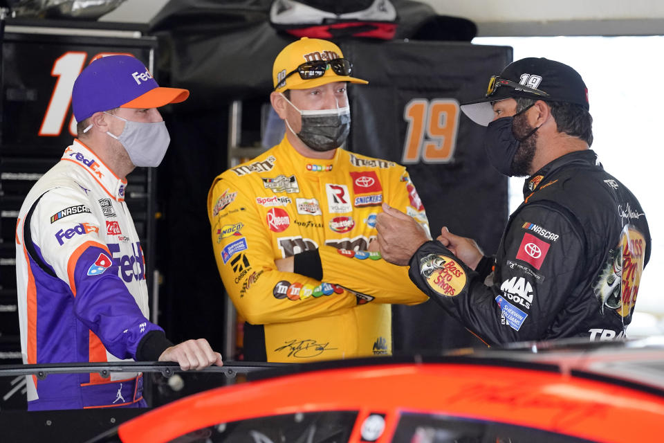 Denny Hamlin, left, Kyle Busch, center and Martin Truex Jr. talk in a garage before the start of a NASCAR Daytona 500 auto race practice session at Daytona International Speedway, Wednesday, Feb. 10, 2021, in Daytona Beach, Fla. (AP Photo/John Raoux)