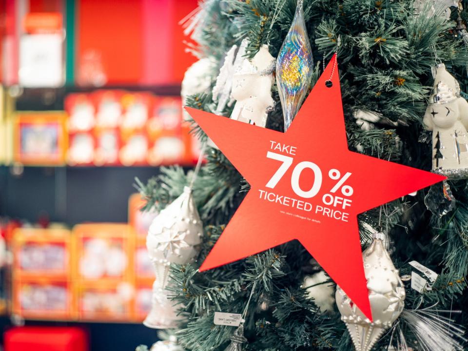 Star shaped tag that reads 70% off hangs on Christmas tree inside store