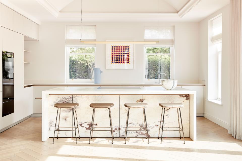 The kitchen walls are painted White Dove by Benjamin Moore while the chevron floor is pale oak, rather than the dark oak of the more formal reception rooms. The bar stools are by Gubi. Linen curtains by Mary Wrynne soften the space and filter out any strong light.