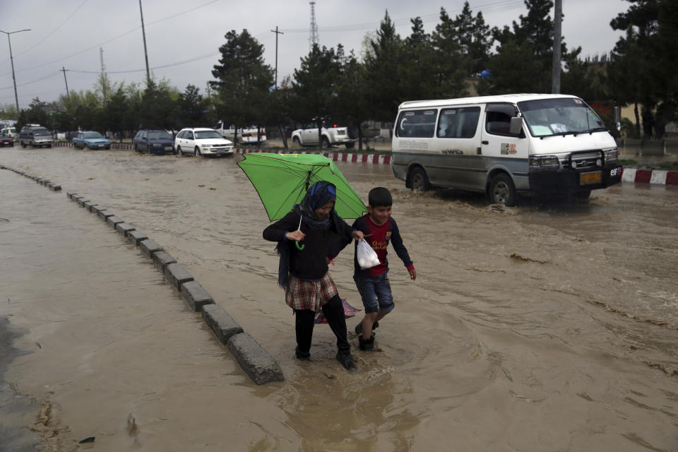 An Afghan girl and a boy walk through floodwaters as heavy rain falls in Kabul, Afghanistan, Tuesday, April 16, 2019. Afghan officials say at least five more people have been killed and 17 are missing as a new wave of heavy rains and flooding swept across the country's western Herat province. (AP Photo/Rahmat Gul)