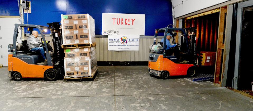 Chatham operations manager Brad Walton, left, and volunteer leader Bill Ridgley use forklifts to load donations onto a truck for earthquake victims in Turkey at the Midwest Missions Distribution Center Friday.