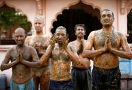 People pray after applying cow dung on their bodies during "cow dung therapy" on outskirts of Ahmedabad