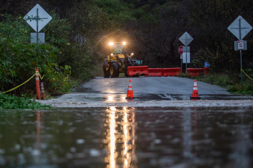 City workers close a road after a creek overflows during heavy rains in Zuma Beach during heavy rains on Dec. 21, 2023 in Malibu, California.