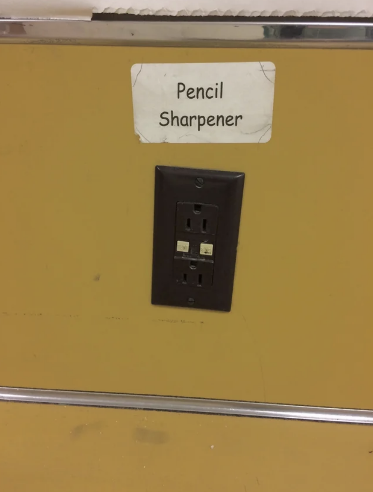 A label says "pencil sharpener" right above an electrical wall outlet