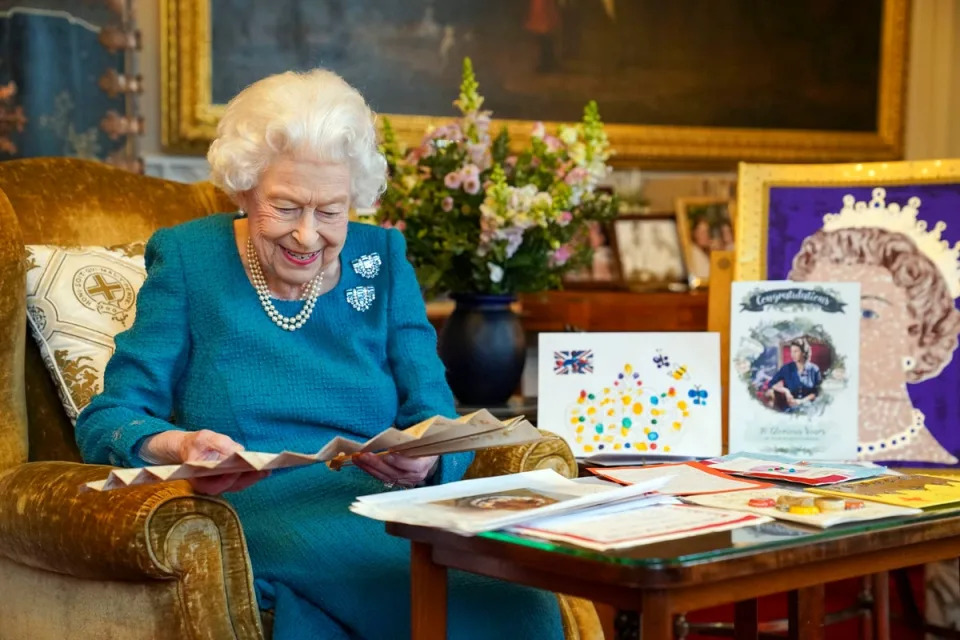 Queen Elizabeth II looks at a fan as she views a display of memorabilia from her Golden and Platinum Jubilees in the Oak Room at Windsor Castle. (PA)