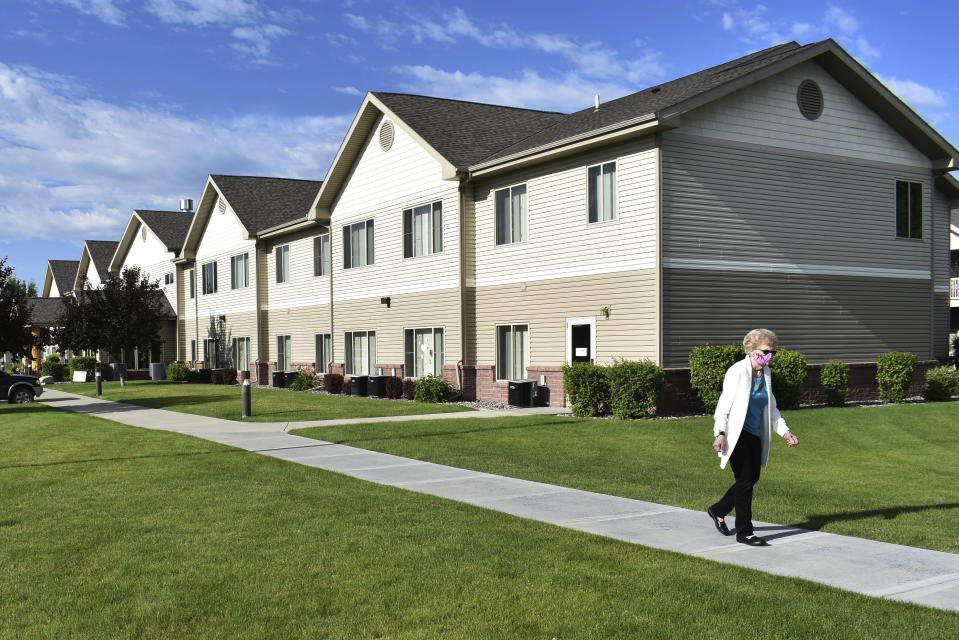 A woman wearing a face mask is seen walking at the Sweetwater Retirement Community in Billings, Mont. on Friday, July 10, 2020. The facility is one of several dozen in Montana that state officials say declined free COVID-19 testing of residents and staff. (AP Photo/Matthew Brown)