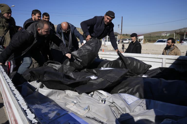 Hombres cargando cuerpos de víctimas sirias para su traslado a Siria en la localidad  de Cilvegozu, en el sur de Turquía y junto a la frontera siria, el jueves 9 de febrero de 2023.