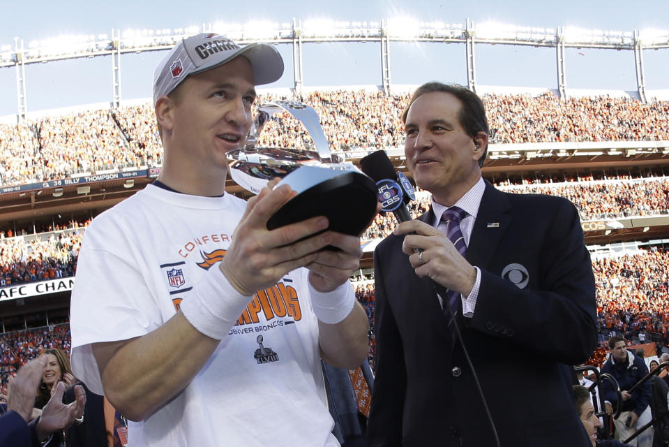 Denver Broncos quarterback Peyton Manning, left, accepts the championship trophy after the AFC Championship NFL playoff football game in Denver, Sunday, Jan. 19, 2014. The Broncos defeated the Patriots 26-16 to advance to the Super Bowl. (AP Photo/Charlie Riedel)