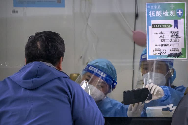 Una trabajadora, equipada con un traje de protección, realiza un test de detección del COVID-19 en un centro de pruebas en Pekín