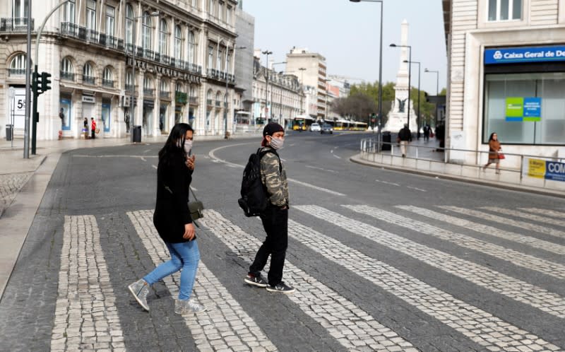 Tourists wearing protective masks as a preventive measure against coronavirus disease (COVID-19) walk at Rossio Square in downtown Lisbon