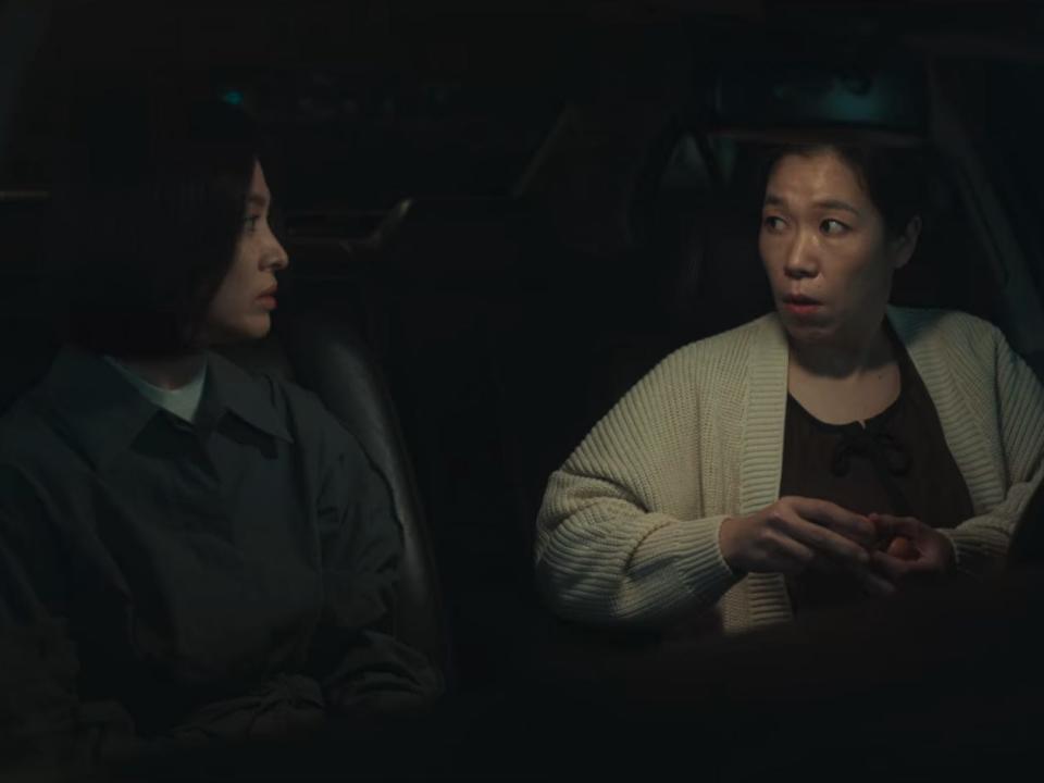 dong-eun and hyeon-nam in a car. hyeon-nam, illuminated by the light above the dashboard, has a confused expression on her face