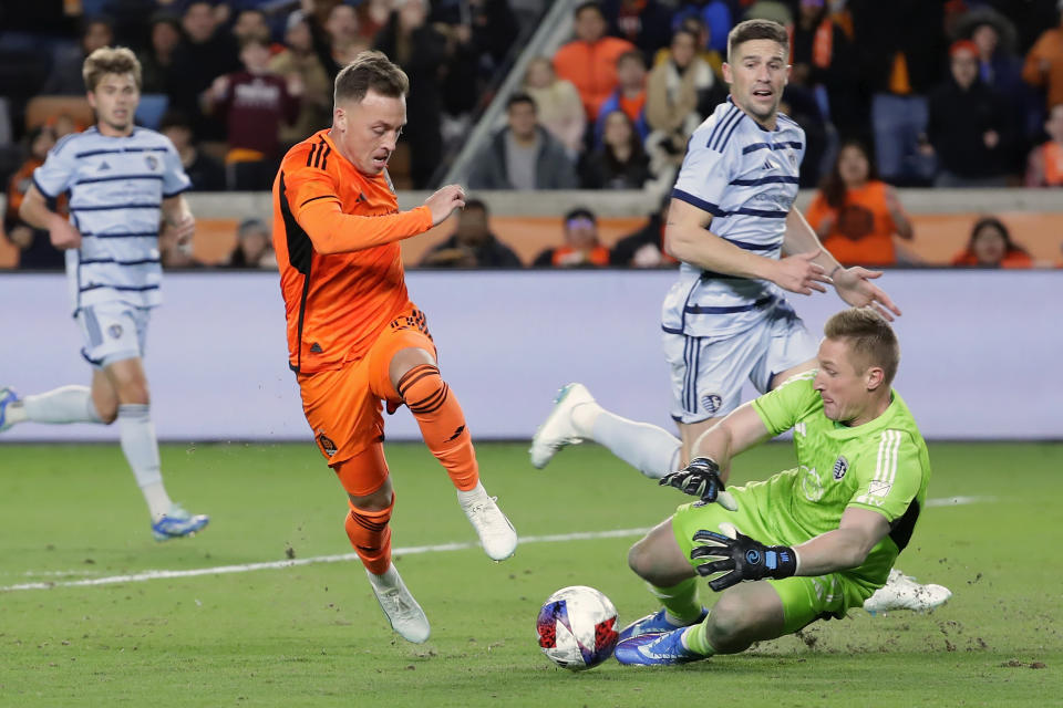 Houston Dynamo forward Corey Baird, center left, attempts to shoot on goal as Sporting Kansas City goalkeeper Tim Melia, front right, makes a stop and Sporting's Khiry Shelton, back left, and Andreu Fontas, back right, look on during the second half of an MLS playoff soccer match Sunday, Nov. 26, 2023, in Houston. (AP Photo/Michael Wyke)