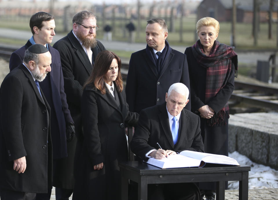 United States Vice President Mike Pence writes in the guest book during his visit at the Nazi concentration camp Auschwitz-Birkenau in Oswiecim, Poland, Friday, Feb. 15, 2019. His wife Karen on his left, Poland's President Andrzej Duda and his wife Agata Kornhauser-Duda on the right. (AP Photo/Michael Sohn)