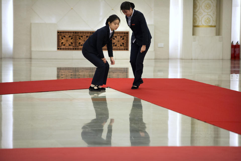 Staff members adjust a red carpet before a welcome ceremony for Pakistan's Prime Minister Imran Khan at the Great Hall of the People in Beijing, Saturday, Nov. 3, 2018. (AP Photo/Mark Schiefelbein)