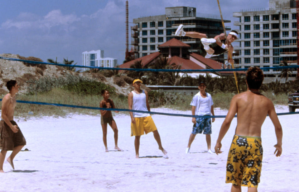 Steve-O leaping over a volleyball net with a pole vault