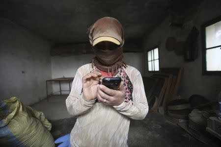 A 29-year-old woman (who asked to withhold her name) is covered in cannabis dust while talking to her family in Raqqa on her mobile phone inside a garage in the Bekaa valley, Lebanon November 1, 2015. REUTERS/Alia Haju