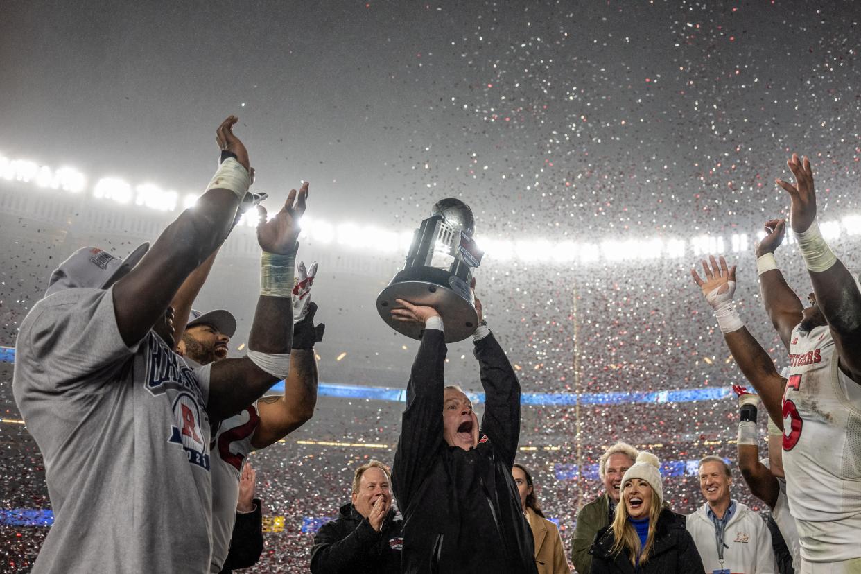 Dec 28, 2023; Bronx, NY, USA; Rutgers Scarlet Knights head coach Greg Schiano lifts the trophy with Rutgers Scarlet Knights running back Kyle Monangai (5) and Rutgers Scarlet Knights quarterback Gavin Wimsatt (left) to celebrate the win against the Miami Hurricanes at Yankee Stadium. Mandatory Credit: Mark Smith-USA TODAY Sports