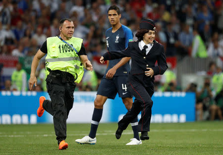 Foto del domingo de un guardia de seguridad persiguiendo a una miembro de la banda Pussy Riot que había invadido el campo de juego en la final del Mundial. Jul 15, 2018 REUTERS/Damir Sagolj