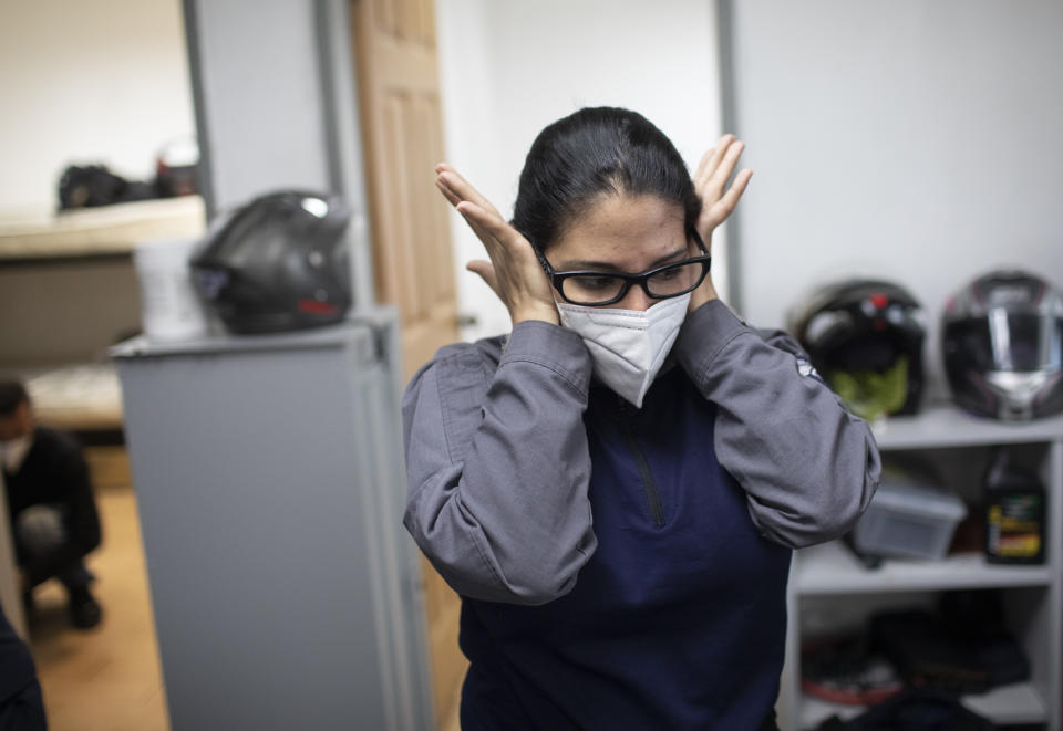 Wearing a mask as a precaution against the new coronavirus, Angels of the Road volunteer paramedic Zully Rodiz rubs her face at the end of her shift at the group's operations base in Caracas, Venezuela, Monday, Feb. 8, 2021. The self-sufficient volunteers seek their own funding and operate entirely independently from the government. (AP Photo/Ariana Cubillos)