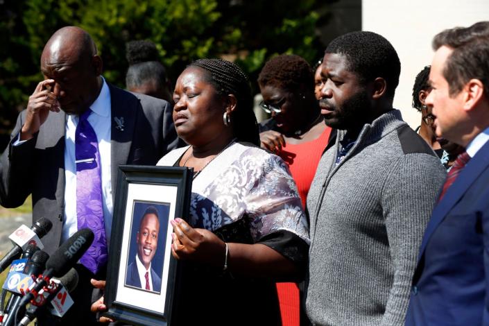 Caroline Ouko, mother of Irvo Otieno, holds a portrait of her son with attorney Ben Crump, left, her oldest son, Leon Ochieng, and attorney Mark Krudys at Dinwiddie Courthouse in Dinwiddie, Va. (AP)