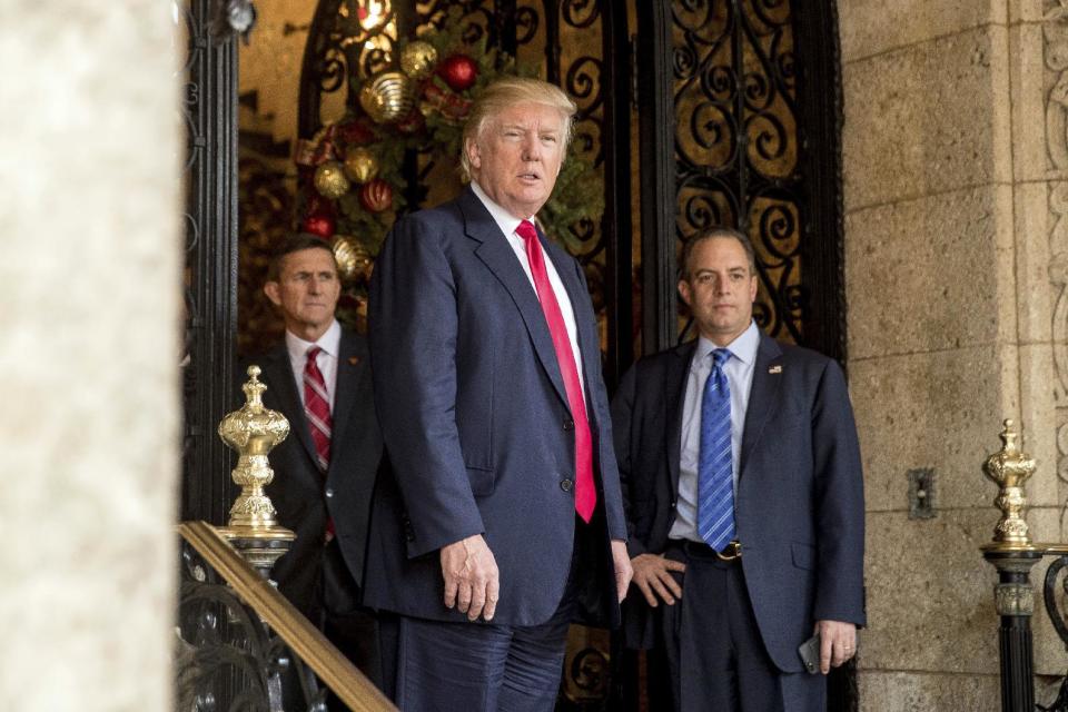 President-elect Donald Trump, center, accompanied by Trump Chief of Staff Reince Priebus, right, and Retired Gen. Michael Flynn, a senior adviser to Trump, left, takes a question from a member of the media at Mar-a-Lago, in Palm Beach, Fla., Wednesday, Dec. 21, 2016. (AP Photo/Andrew Harnik)