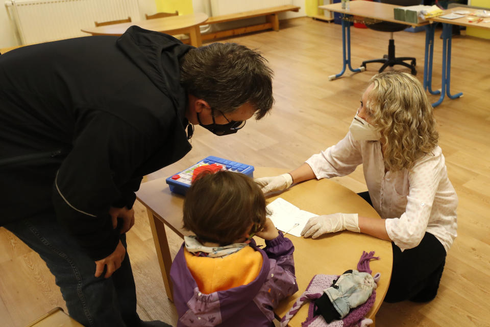 A young girl waits for the result of rapid COVID-19 test before entering her class at a kindergarten in Prague, Czech Republic, Monday, April 12, 2021. The Czech government has agreed to start easing the tight lockdown in one of the hardest-hit European countries and has given a green light for at least some children to return to schools. (AP Photo/Petr David Josek)