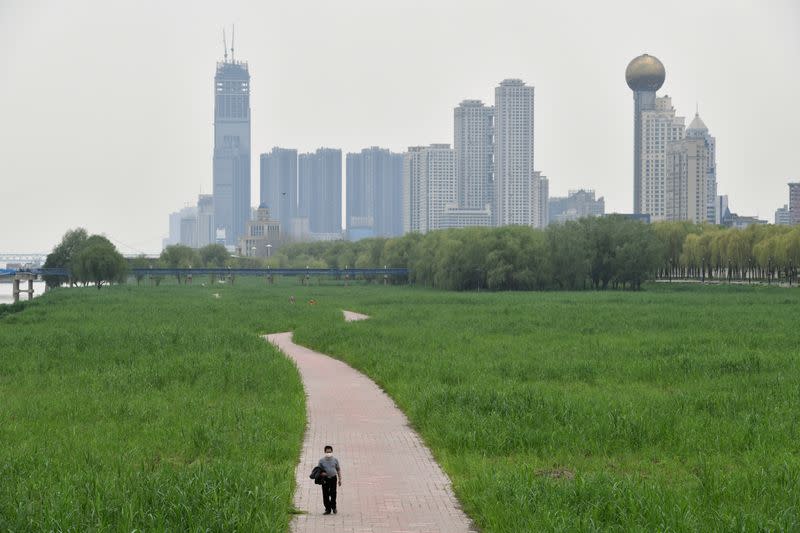 Man wearing a face mask walks at a riverside park in Wuhan