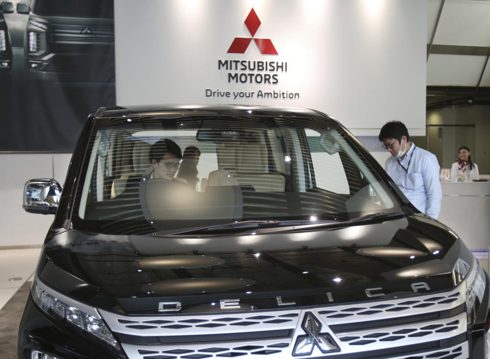 FILE - In this Monday, Nov. 26, 2018, file photo, people look at Mitsubishi car at headquarters of Mitsubishi Motors Corp in Tokyo. German-U.S. automaker Daimler Chrysler bought a 37 percent stake in Tokyo-based Mitsubishi Motors Corp. in 2000, but the alliance felt rocky from the start. Mitsubishi Motors was embroiled in a years-long scandal over its systematic cover-up of auto defects. (AP Photo/Koji Sasahara, File)