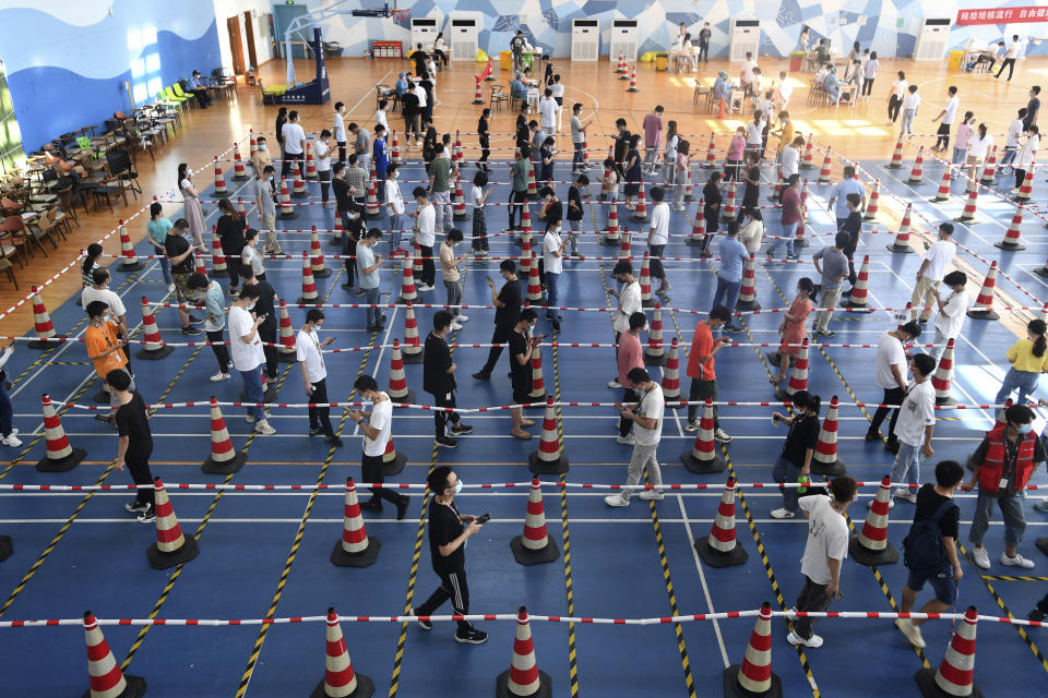 Workers from the China Star Optoelectronics Technology (CSOT) company line up for mass coronavirus test in a gym during a round of COVID-19 test in Wuhan in central China's Hubei province on Aug. 5, 2021. More than 30 Chinese officials have been fired or received other punishments over accusations they failed to respond properly to the latest surge of the coronavirus in the country. (Chinatopix via AP)