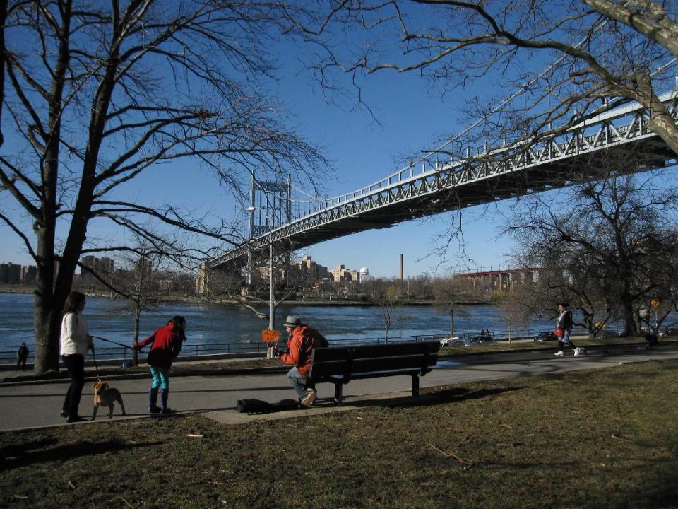 This March 9, 2013 photo shows visitors at Astoria Park in the New York City borough of Queens. It's one of several waterfront parks in Astoria and the adjacent neighborhood of Long Island City. The area also offers museums, a variety of ethnic restaurants and moderately priced hotels with easy access to Manhattan. The photo also shows the Triborough Bridge connecting Queens with the Bronx across the water. (AP Photo/Beth J. Harpaz)