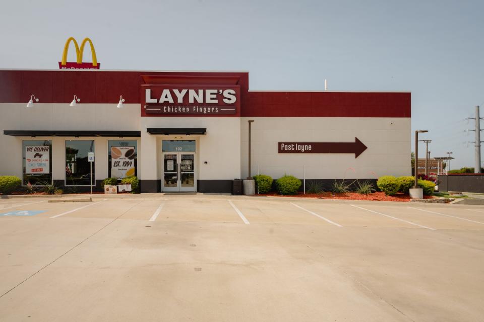 A parking lot outside a fast food restaurant with a white and red facade on a sunny day.