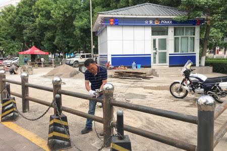 A man installs fencing in front of a police station in Yili, Xinjiang Province, China May 17, 2017. REUTERS/Sue-Lin Wong