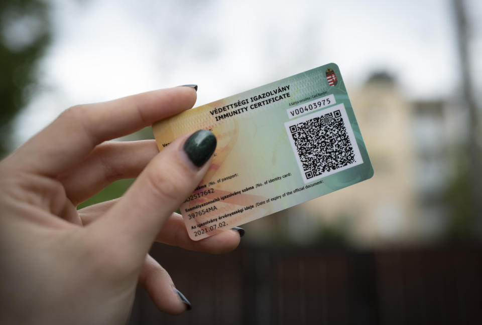 An Hungarian woman shows her government-issued COVID-19 immunity card in Budapest, Hungary on Friday April. 30, 2021. Beginning Saturday morning, card holders may access indoor dining rooms, hotels, theaters, cinemas, spas, gyms, libraries, museums and other recreational venues. The latest round of re-openings, which the government has tied to the number of administered vaccines, will come as Hungary reaches 4 million first-dose vaccinations, representing about 40% of the population. (AP Photo/Bela Szandelszky)