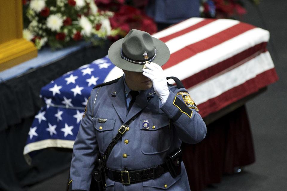 A Georgia State Trooper stands near the casket of Americus Police Officer Nicholas Smarr at the Georgia Southwestern State University Storm Dome before a funeral service, Sunday, Dec. 11, 2016, in Americus, Ga. Smarr, died after responding to a domestic disturbance call in a Wednesday morning attack. His lifelong friend, university campus Officer Jody Smith, was critically wounded after arriving on the scene as backup to Smarr, and later died from his injuries Thursday. (AP Photo/Branden Camp)