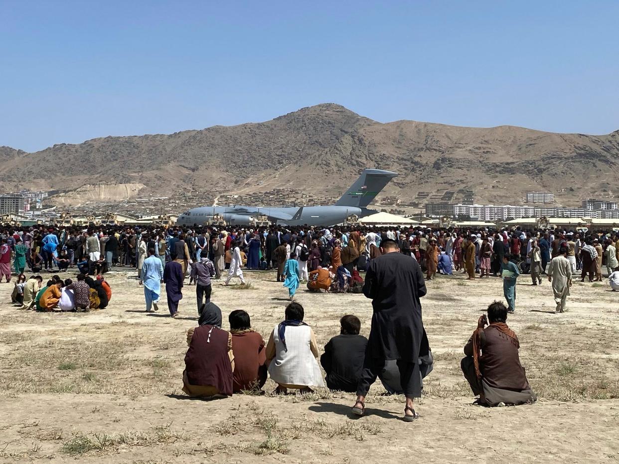 Hundreds of people gather near a U.S. Air Force C-17 transport plane at the perimeter of the international airport in Kabul, Afghanistan, Aug. 16, 2021.