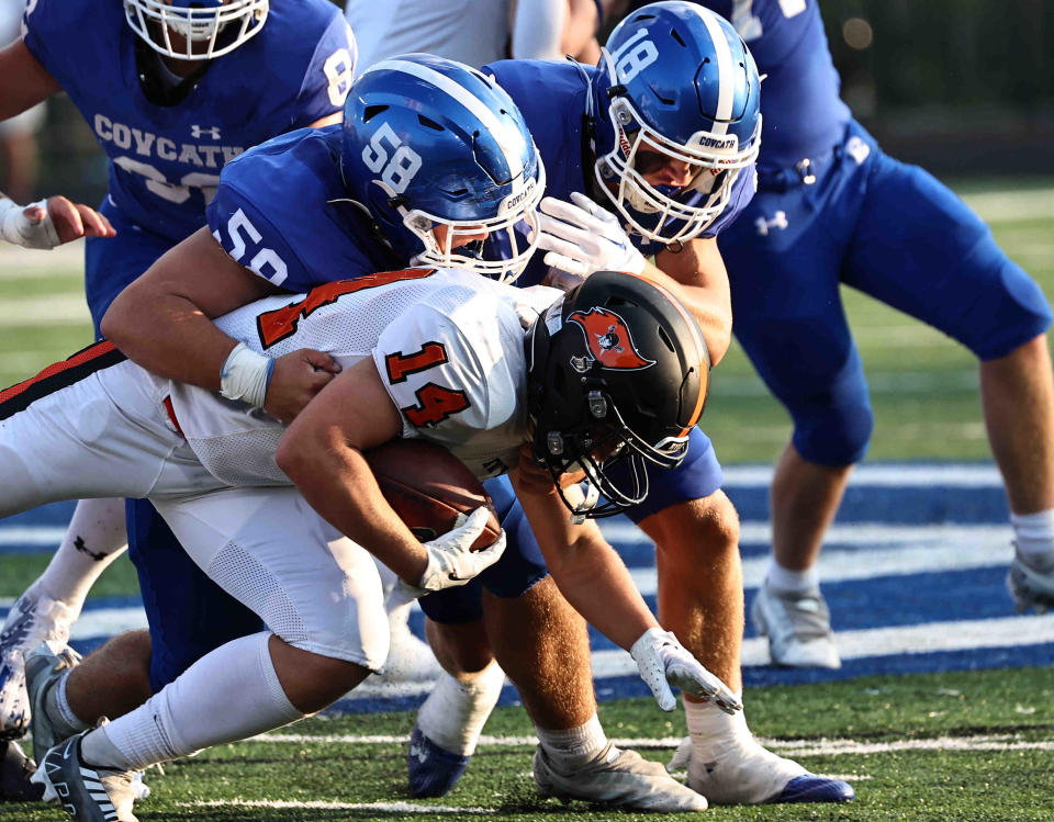 Ryle's Brayden Elder (14) is tackled by Covington Catholic defenders Isaac Mason (58) and Cash Harney (18) during their football game Friday, Aug. 18, 2023.