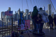 Tourists take a video with the help of a vendor working on the Brooklyn Bridge in New York, Tuesday, Jan. 2, 2024. New York City will ban vendors from the Brooklyn Bridge starting Wednesday, Jan. 3, 2024. The move is intended to ease overcrowding on the famed East River crossing, where dozens of souvenir sellers currently compete for space with tourists and city commuters. (AP Photo/Seth Wenig)